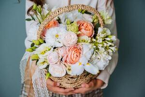 A girl in a white shirt and plaid skirt holds a basket of flowers. Gift for the teacher for the first of September. photo