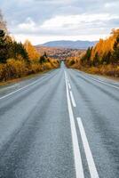 un largo asfalto la carretera yendo a el montañas, alrededor el otoño bosque y montañas. viaje con tu familia por auto, relajarse en naturaleza y Fresco aire. foto