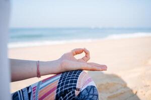 The hand is folded in a meditation pose. Meditation and yoga on the seashore. Tranquility, peace and the search for harmony. Relax on the beach photo