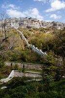 un amurallado ciudad en el montañas. antiguo histórico edificios, un excursionismo sendero para turistas ver de el montaña picos en un brillante soleado día foto