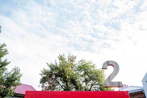 Two. Number two. A large wooden sign in the form of the number Two is installed on the roof. Signage against the backdrop of an incredible beautiful cloudy sky. photo