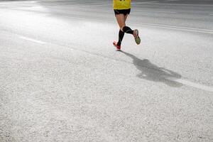 Sport. Jog. A person is engaged in running on asphalt road. A man in bright sneakers, a T-shirt and gaiters runs down the road on a sunny day. photo