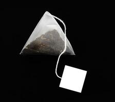 Pyramid shape teabag isolated on the dark background photo