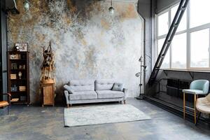 interior shot in the studio. loft studio. a large panoramic window that transmits a lot of light, an unusual decorative wall, A bookcase full of books. a chic gray sofa. Arrangement of furniture. photo