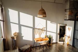 Interior picture of the room in the loft style in the bright rays of the sun. Wooden table, succulents and cacti, a large mirror and a decorative pano on the wall. photo