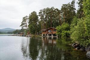 Panoramic view of the quiet lake and wooden house right by the water. Outdoor recreation. photo