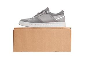Grey casual sports shoes sneaker on a brown cardboard box isolated on a white photo