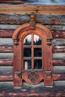 Old wooden window with beautiful carved platbands. Wooden architecture. A small window in the house made of logs. Rustic style photo