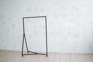 Metal hanger floor on a minimalist background. Rack for clothes on wheels. Light walls, wooden floor in the room. photo