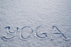yoga en invierno. un inscripción en el nieve. el palabra yoga es escrito en el nieve. un minimalista imagen de zen budismo. paz y tranquilidad. foto