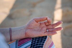 cerca disparar de un mano es doblada en un meditación pose. meditación y yoga en el costa. tranquilidad, paz y el buscar para armonía. relajarse en el playa foto