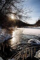 soleado primavera clima se derrite el hielo en el río. el belleza de ruso naturaleza. invierno paisaje. descongelado el río. piedras en el agua son cubierto con nieve. Brillo Solar Mañana foto