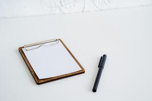 A blank sheet of paper and a pen lie on a white background. Touchscreen with sheets. Writing down thoughts and plans. photo