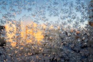 The texture of the glass covered with frost in winter in cold. Magical winter patterns on the glass. Natural phenomena. Frozen water on the window. photo