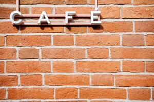 Wooden sign of the caf against the background of a brick wall. Sign at the institution, the name of the cafe photo