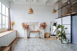 Interior shot. Bright room of the studio. There are two vases with leaves . The main element of the room vases, macrame and orange table photo