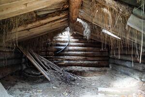 An old and cluttered attic on a wooden roof. There is a window on the roof. photo