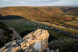 Sunset puddles of the sun on the rock. In the valley under the rock there are houses. photo