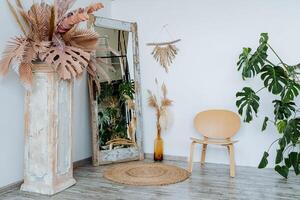 Interior shot. Bright room of the studio. There is a vase with piles of wheat Interesting wooden table. The main element of the room a wicker mat. floor mirror and wooden chair. photo