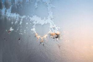 The texture of the glass covered with frost in winter in cold. Magical winter patterns on the glass. Natural phenomena. Frozen water on the window. photo