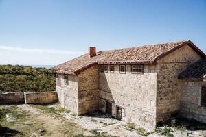 antiguo casa con un embaldosado techo en el montaña llanuras. grande Roca casa. brillante azul cielo, claro montaña aire y verde bosques descanso en el montañas foto