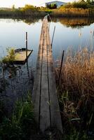 A long wooden bridge passing through a small lake with reeds. photo