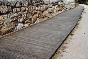 A wooden path going far ahead. The path to the sea, the sandy shore, the fence and the fence of stone. Walk in the fresh air, equipped sea area photo