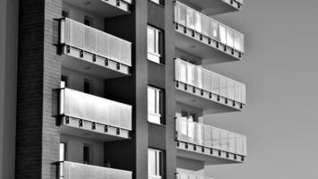 Fragment of the building's facade with windows and balconies. Modern apartment buildings on a sunny day. Facade of a modern residential building. Black and white. photo