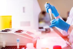 Professional laboratory technician fills vial with liquid and puts in the rack. photo