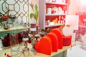 preparación para un fiesta con rojo corazón conformado cajas, velas, regalos, flores en el habitación. hermosa composición de rojo corazones y rosas, tulipanes, florero y bonito velas para especial día foto