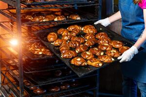 Baker presenting tray with pastry or dough in bakery photo