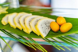 Creative concept with sliced exotic fruits and three small oranges on the green leaf. Exotic fruits in the open air. Closeup photo