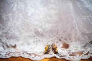 dos elegante Boda anillos en un blanco vestir antecedentes. romántico accesorios para novia y novio. Boda joyas. de cerca foto