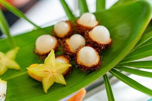 Tropical fruits on a big green leaf outside for guests. Exotic fruit as package design element. Close-up photo