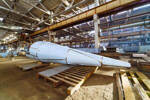 Huge tube on the background of modern engineering factory. A big construction on the wooden stand inside the factory. photo