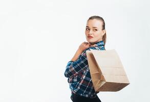 Portrait pensive beautiful woman holding package with purchases after shopping isolated on white background. Attractive young thoughtful model with a shopping bag. photo