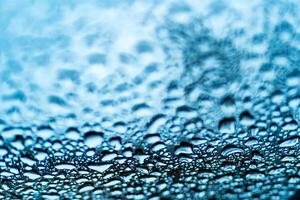 Bright clear bubbles of water drops on the window after the rain on blue background. Drops of rain on the glass.Macro shot photo