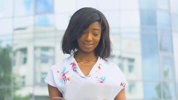 Adult african american young business woman works with documents near modern office building video