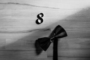 negro corbata de moño y Boda anillos acostado en el formar de un número ocho en de madera antecedentes. Boda accesorios aislado en gris. foto
