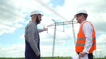 dois engenheiros trabalhando perto transmissão linhas. Gerente aceita uma relatório em a Operação do poder linhas video