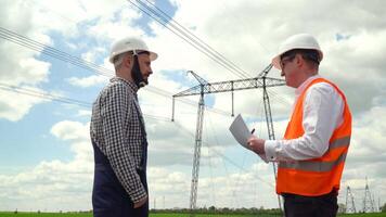 dois engenheiros trabalhando perto transmissão linhas. Gerente aceita uma relatório em a Operação do poder linhas. energia eficiência concepção video