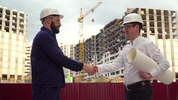 Architect or engineer working, browsing building project of construction site with blueprint plan. Builders shaking hands video