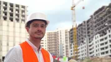 portret van een geslaagd jong ingenieur, architect, bouwer, zakenman, vervelend een wit helm, in een overhemd Aan een bouw plaats video