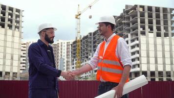 arquiteto ou engenheiro trabalhando, navegando construção projeto do construção local com projeto plano. construtores tremendo mãos. construção construção conceito video