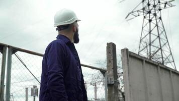 ingeniero en especial uniforme en pie con tableta cerca poder estación. energía eficiencia concepción video