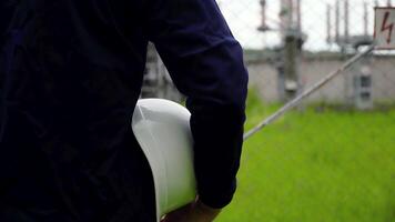 Worker in a uniform and a white helmet on the background of power station video