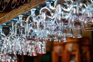 Empty clean glasses for champagne hanging over the bar counter. Crystal glasses for alcohol hung in the bar. Close-up photo