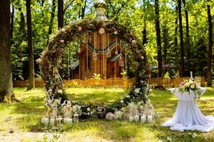 Arch for the wedding ceremony. Decorated with fabric flowers and greenery. Is located in a pine forest. Background church. Wedding decorations in rustic style. Just married. Wedding decor photo