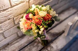 hermosa nupcial ramo. rosas cerca el blanco ladrillo pared. Clásico antecedentes. Boda accesorios de cerca. foto