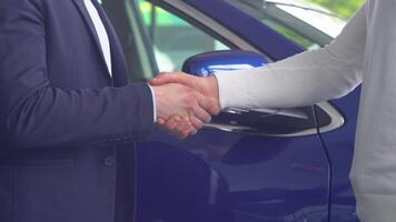 Auto seller and a man who bought a vehicle shake hands. Technology and people concept video